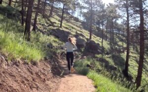 Dr. Chloe trail running through a wooded area on a sunny day